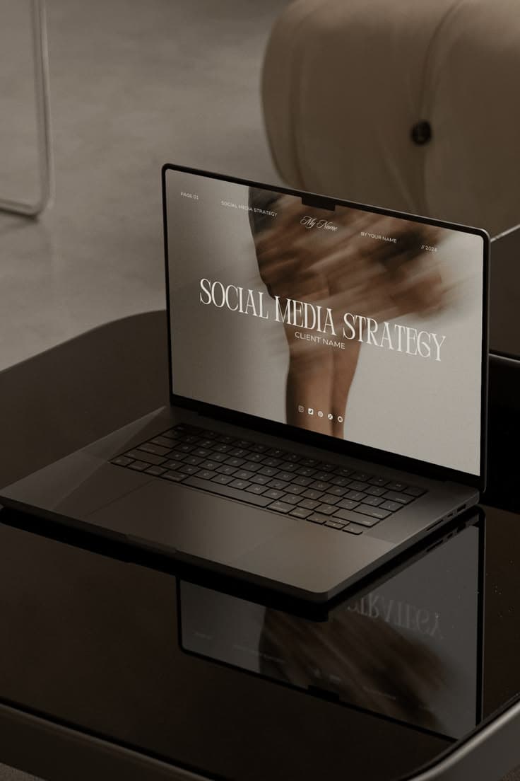 A sleek laptop on a reflective table displaying a social media strategy presentation slide.