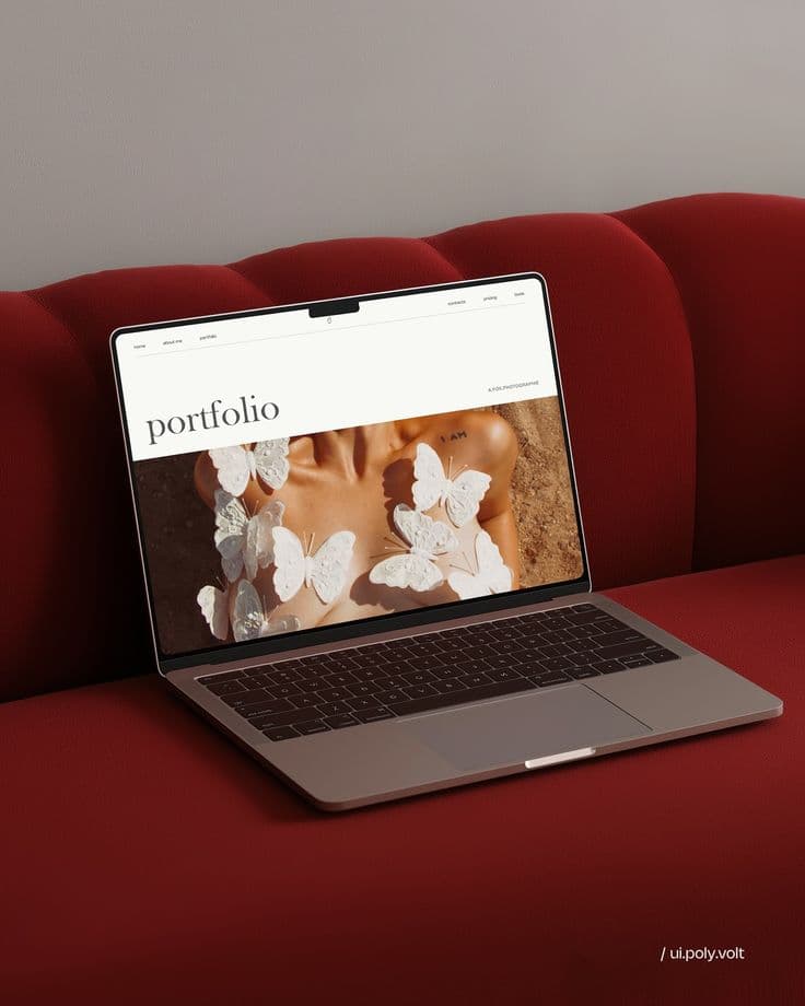 Laptop displaying a creative portfolio website resting on a textured red velvet sofa.